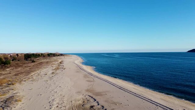 Low aerial pan of beautiful sandy beach on sunny day. Greece.