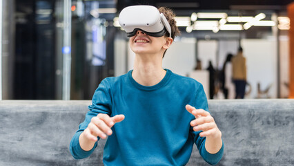 An excited young man exploring virtual reality using VR glasses in an office