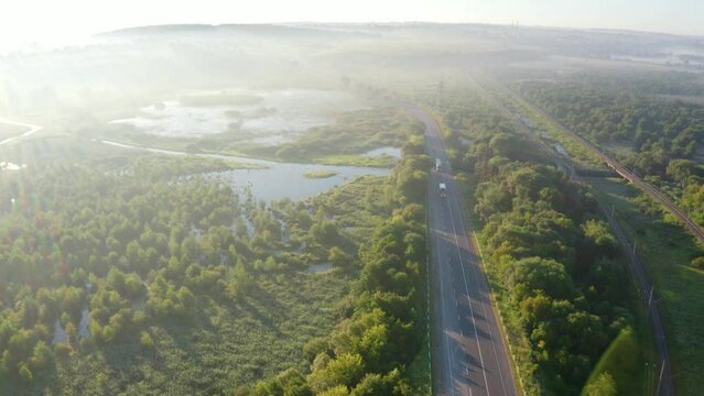 4k drone flight down footage (Ultra High Definition) of Seret river in Ternopil outskirts, Ukraine, Europe. Aerial summer view of asphalt road in the morning mist. Traveling concept background.