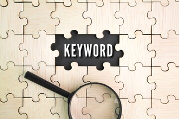 wooden puzzle and a magnifying glass with the word keyword in the middle hole of the puzzle. the...
