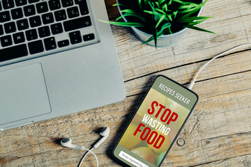 Stop wasting food app design on a mobile phone screen placed on a work desk. - 571183372