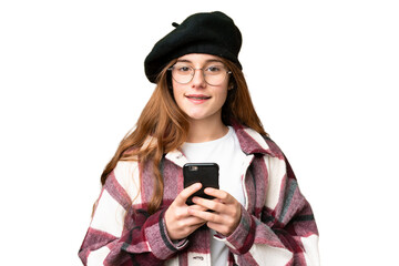 Teenager girl over isolated chroma key background looking at the camera and smiling while using the mobile