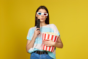 woman with remote control watching interesting movie and holding bucket of popcorn