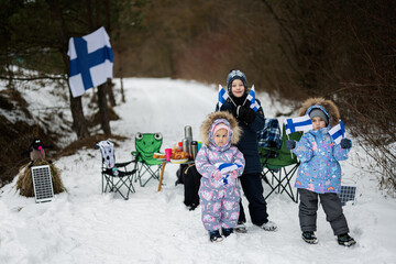 Three finnish children with Finland flags on a nice winter day. Nordic Scandinavian people.