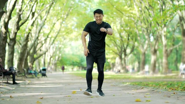 Young Asian Runner Athlete With Muscle Pain In An City Park. Man Massaging Stretching, Trauma Injury While Jogging Outdoors. Fitness Male Sprain Severe Pain Stretch Pull. Leg Muscle Cramp Calf Sport