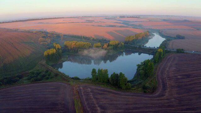 4k drone flight back footage (Ultra High Definition) of summer sunrise on Ternopil outskirts with two lakes and asphalt road on the midle. Impressive morning view of hte Ukrainian countryside.