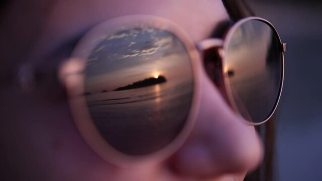 Portrait of pretty woman in sunglasses at the sea at sunset. Close up