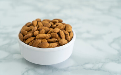 Almond in a white bowl on marble table, copy space image