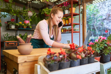 Female florist using mobile phone and computer in flower shop