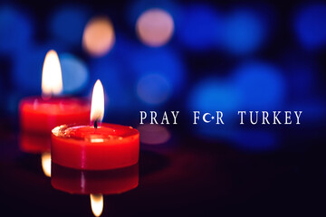 pray for turkey text with candle over dark bokeh background.