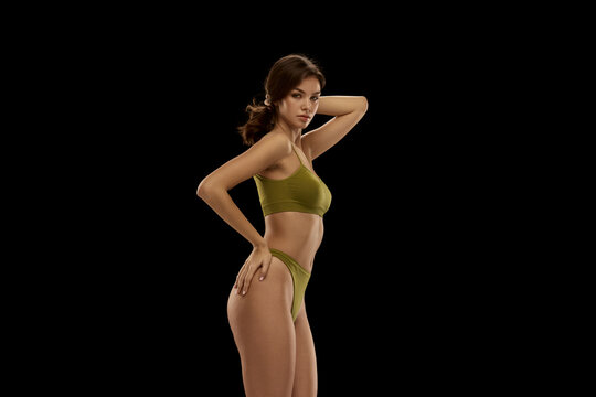 Portrait of young attractive woman posing in olive color lingerie isolated over black background. Concept of beauty, body and skin care, health, plastic surgery, cosmetics, ad