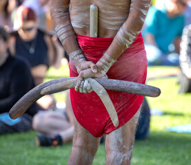 Australian Aboriginal culture, a man is holding boomerangs behind his back, the ritual rite at the community event, symbol of indigenous culture and traditions - obrazy, fototapety, plakaty