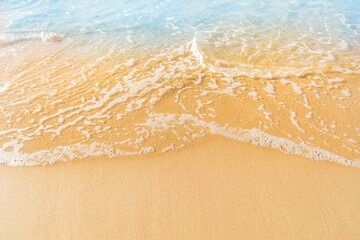 Close-up of a beach with a calm transparent wave. Romantic sea coast with golden sand.