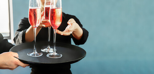 glass of red wine served by a professional caterer on blurred blue grey background