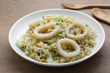 fried rice with squid in a ceramic dish on wooden table, close up. asian homemade style food concept.