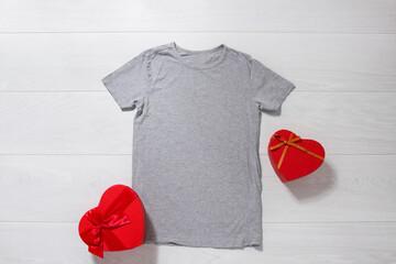 Grey tshirt mockup. Valentines Day concept shirt, gift boxes heart shape on wooden background. Copy space, template blank front view t-shirt clothes. Romantic outfit. Flat lay holiday fashion