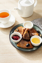 Delicious thin pancakes with jam, honey and soour cream and cup of tea on light wooden table. Morning breakfast concept. Top view with space for text