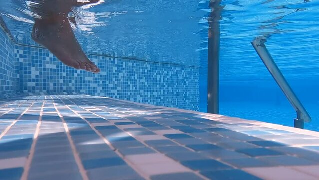 Man and woman entering swimming pool. Detail shot on legs.