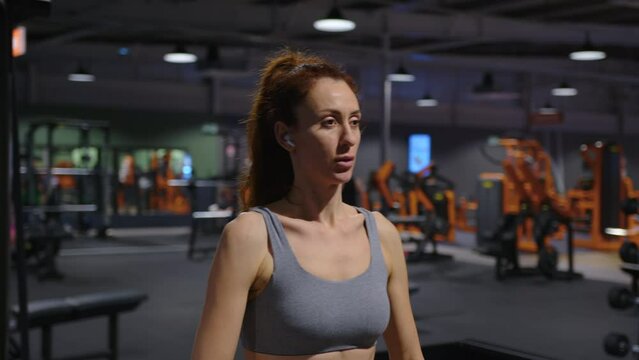 Female athlete doing exercise in sport club. Sporty girl cardio workout. Strong woman fitness training body in dark gym. Bodybuilder working endurance