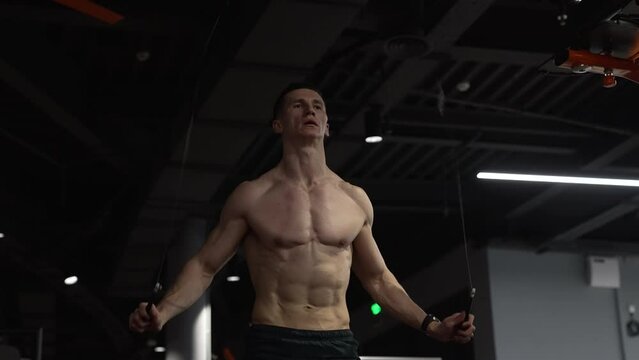 muscular man training with skipping rope in fitness gym. sportsman jumping on skipping rope in gym.