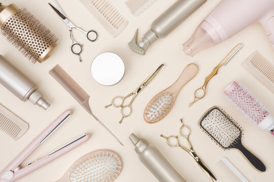 Hairdressing tools and various hairbrushes on cream background top view