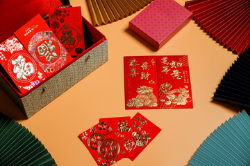 Money cheats and Chinese New Year red packets are placed on an orange background,pictured text: prosperous, springtime text space picture.