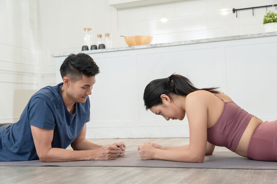 Asian young man laying down on the floor for plank exercises with his girlfriend. Asia couple training for body transformation
