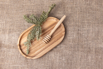 Honey spoon on wooden tray. Burlap background. Natural fabric