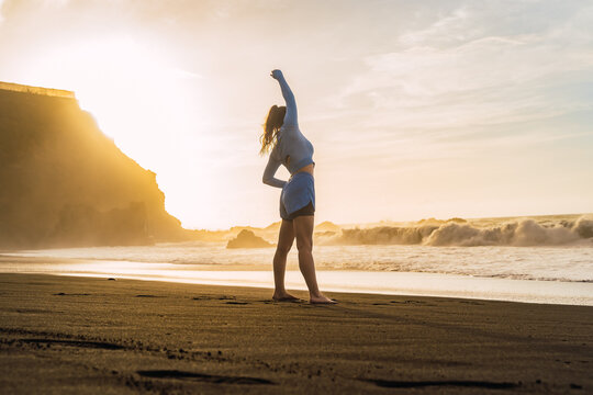 Sporty Woman Stretching Her Shoulders On The Beach.