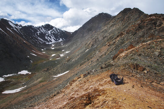 Hiking backpack lying on a mountain rocky pass against the backdrop of dramatic peaks and ridges