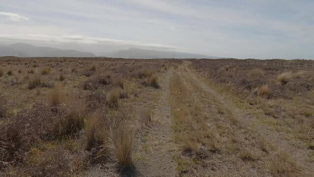 POV off-road cycling on soft sand, dirt and into strong headwind across vast barren landscape (Kaitorete Spit, New Zealand)