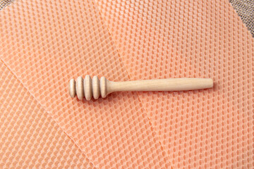 Pink sheets of wax and wooden spoon for honey