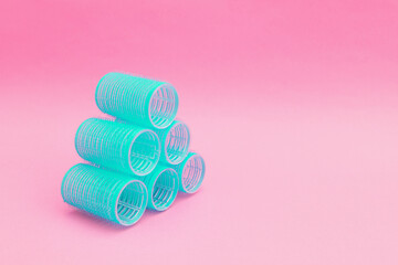 Bright blue hair curlers on a pink background
