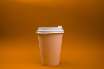 Orange paper cup with white lid on orange background, monochrome