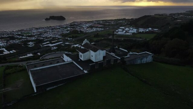 Aerial shot in orbit and during the sunset of the Chapel of Our Lady of Peace and where the sea can be seen. On the island of Sao Miguel, Azores.