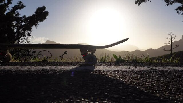 Panning shot of skateboard at mountain sunset on the side of the road