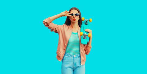 Portrait of cheerful young woman with skateboard on blue background