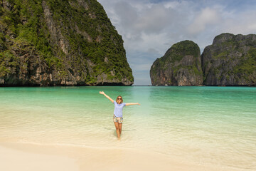 Woman inside the water raising her arms on the lonely beach of maya bay