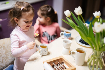 Children eat fruits and desserts, drink tea at home in the evening kitchen.