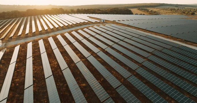 Ecology solar power station panels. Innovation green energy. Alternative energy solar panels aerial view are located on large field near village at sunset in summer slow motion.