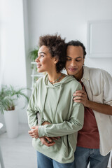 Smiling african american couple hugging at home.