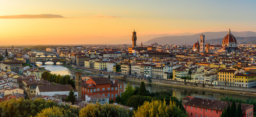 The Florence cityscape with the Ponte Vecchio over Arno river, the Palazzo Vecchio and the Florence Cathedral in an orange sunset.