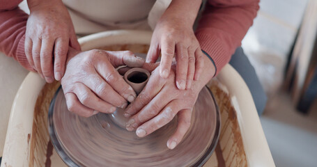 Love, pottery and hands of old couple molding in workshop studio for creative art, support and ceramics class. Trust, marriage and retirement with man and woman with clay wheel on crafting date