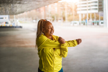 Senior african woman stretching during workout routine outdoor - Focus on face