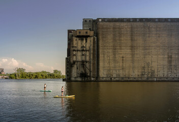 Two people paddleboarding near a large abandoned grain silo © David