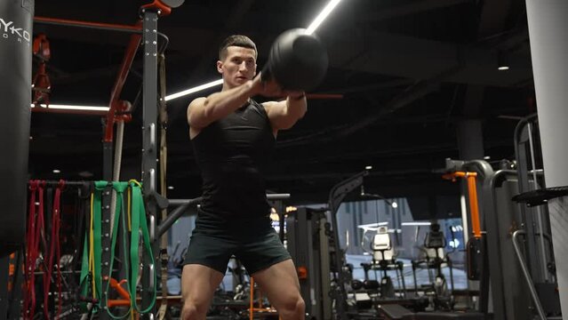 fitness gym. athlete workout with kettlebell. athlete squatting with kettlebell in fitness gym