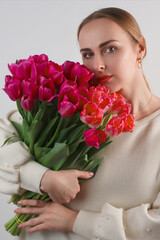 Vertical studio shot of young white woman with bouquet of red tulips.