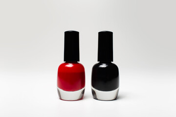 Obraz premium Close-up of glitter nail polish of red and black colours isolated on white background. Two small glass bottles.