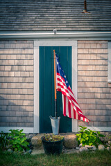 United States flag in front of a Cape Cod style house and door