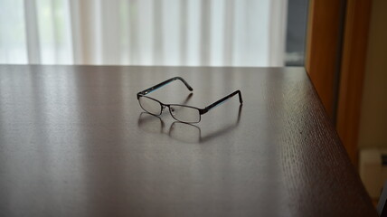 A pair of eyeglasses resting on a reflective table